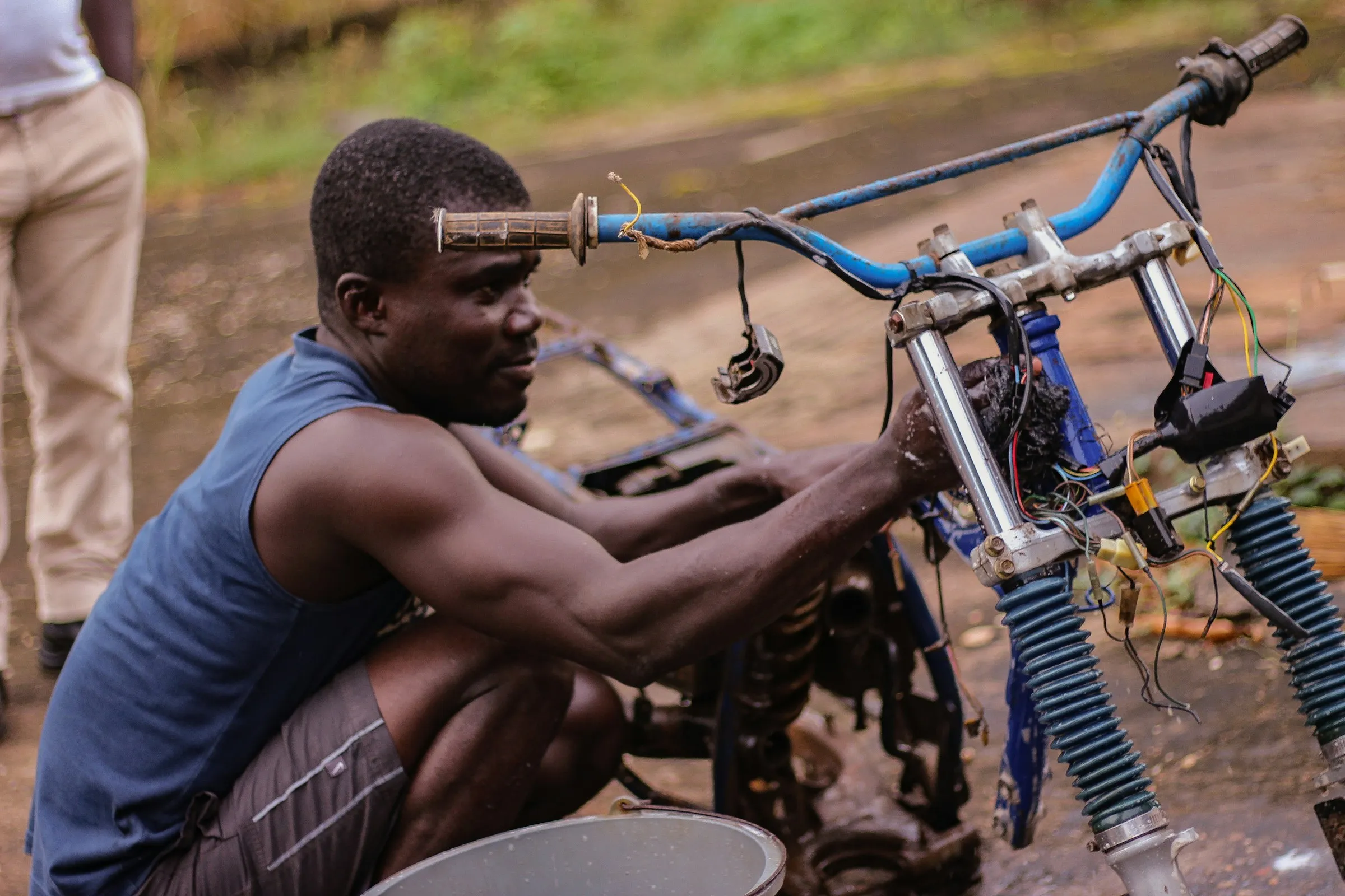 A mechanic repairing a motorcycle at the roadside.